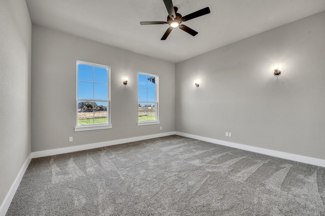 carpeted spare room featuring baseboards and ceiling fan