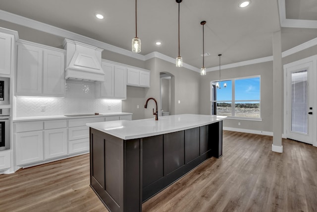 kitchen with custom exhaust hood, ornamental molding, white cabinets, appliances with stainless steel finishes, and backsplash