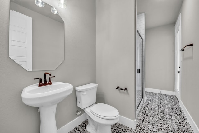 bathroom with toilet, baseboards, and a stall shower