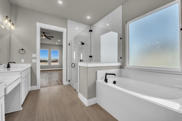 full bath featuring a stall shower, a ceiling fan, a sink, double vanity, and a bath