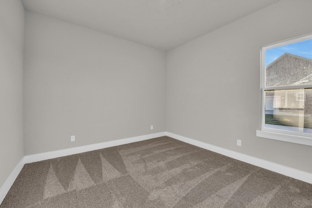 unfurnished room with dark carpet and baseboards