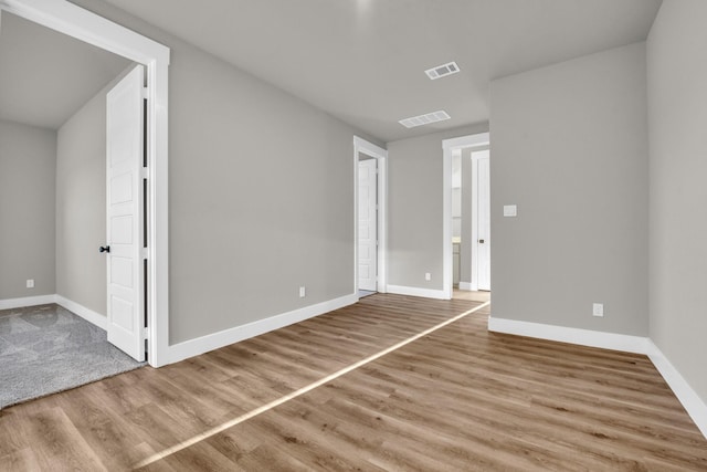 unfurnished room featuring visible vents, baseboards, and wood finished floors