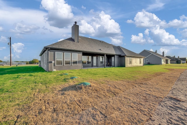 back of property featuring a lawn, a chimney, and a shingled roof