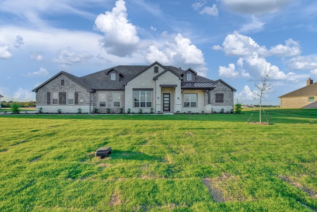 back of property with a yard, stone siding, metal roof, and a standing seam roof