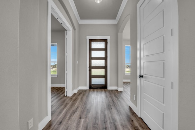 entryway with baseboards, arched walkways, dark wood-type flooring, and crown molding