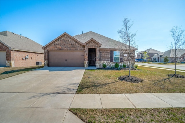 view of front of house with an attached garage, concrete driveway, a front lawn, stone siding, and brick siding
