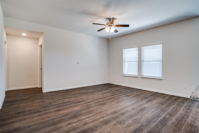 empty room featuring baseboards, dark wood-type flooring, and ceiling fan