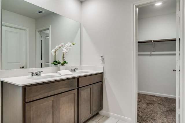 bathroom with double vanity, a spacious closet, visible vents, and a sink