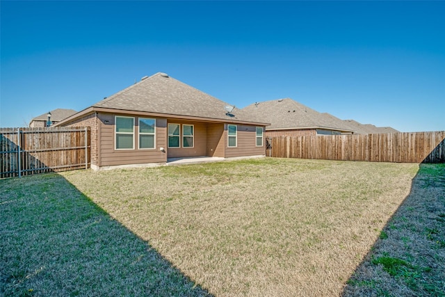 back of property with a yard, a patio, roof with shingles, and a fenced backyard