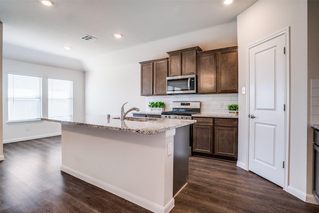 kitchen featuring visible vents, a center island with sink, decorative backsplash, dark wood-style floors, and stainless steel appliances