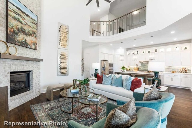 living area with a large fireplace, dark wood-style flooring, recessed lighting, a towering ceiling, and a ceiling fan