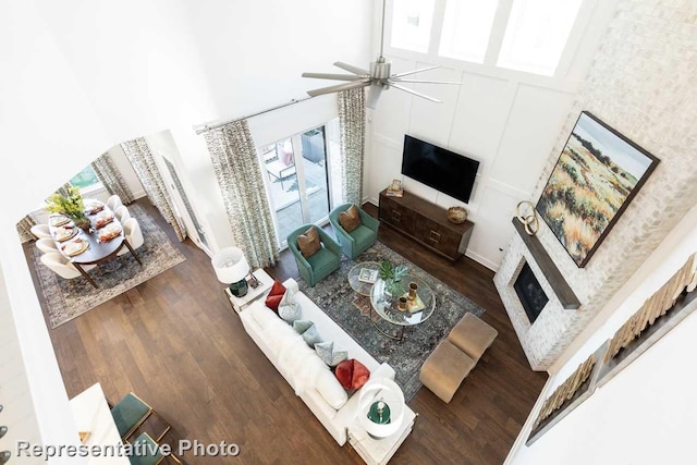 living room with a high ceiling, a ceiling fan, a wealth of natural light, and a glass covered fireplace