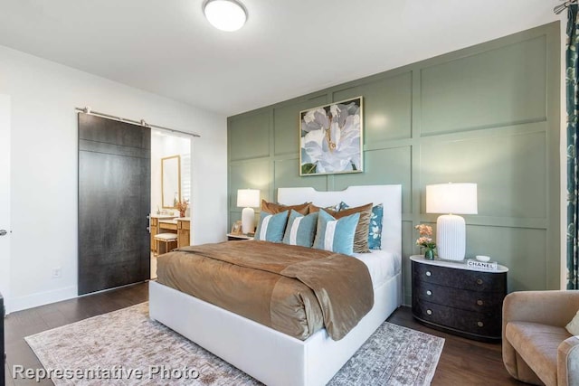 bedroom featuring dark wood-style floors, baseboards, a decorative wall, and ensuite bathroom