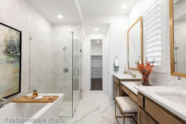 bathroom with double vanity, marble finish floor, a freestanding tub, a sink, and a stall shower