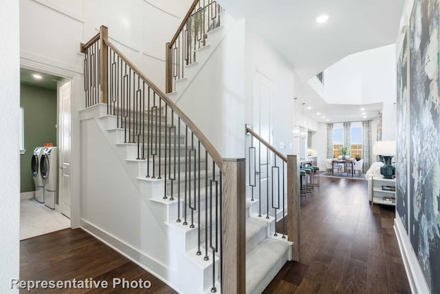 stairs with wood finished floors, washer and dryer, baseboards, and a high ceiling