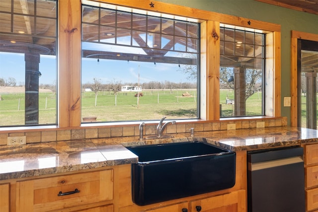 kitchen featuring a sink, a wealth of natural light, and dark stone countertops