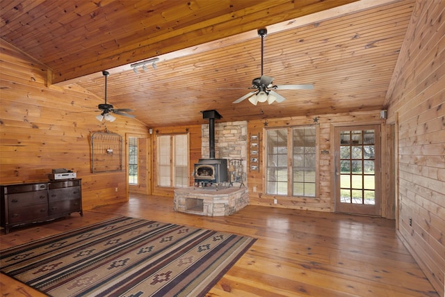unfurnished living room with a wood stove, lofted ceiling, and ceiling fan