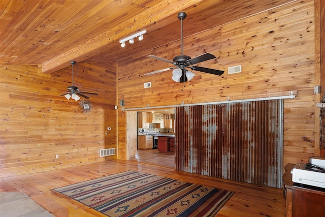 interior space with wooden walls, visible vents, light wood-style flooring, and beamed ceiling