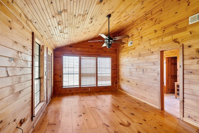 empty room with ceiling fan, light wood-type flooring, wood ceiling, lofted ceiling, and wooden walls