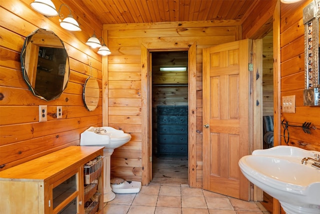 bathroom with tile patterned flooring, wooden walls, wooden ceiling, and a sink
