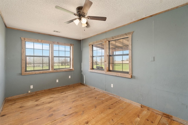 unfurnished room featuring ornamental molding, a textured ceiling, a ceiling fan, visible vents, and wood-type flooring