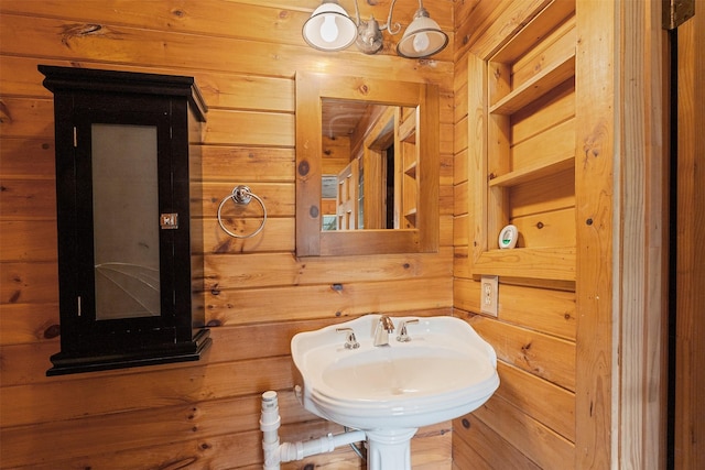 bathroom with wood walls and a sink