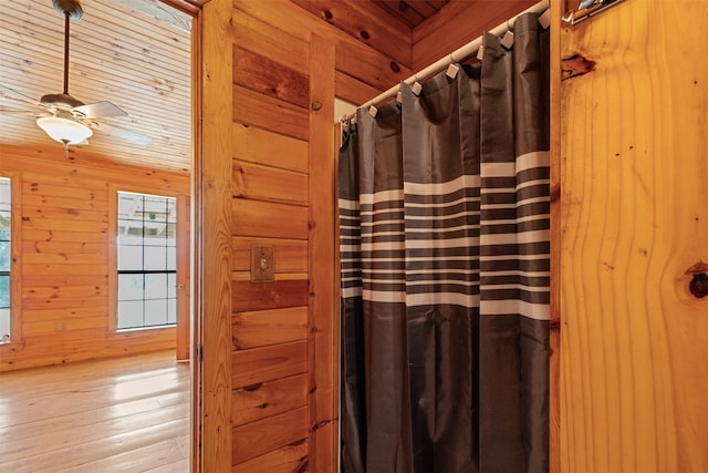 full bath with a shower with shower curtain, wooden walls, a ceiling fan, wood ceiling, and hardwood / wood-style flooring