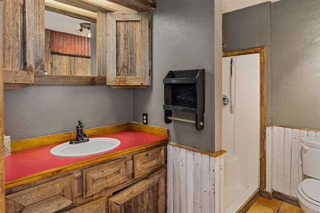 bathroom featuring toilet, a textured wall, radiator, vanity, and tile patterned floors