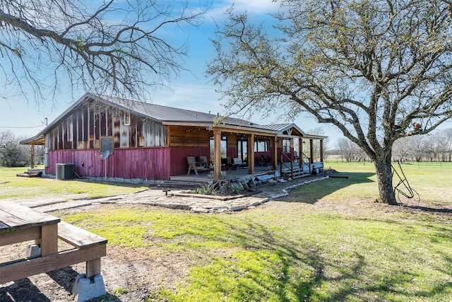 view of side of home featuring metal roof, cooling unit, and a lawn