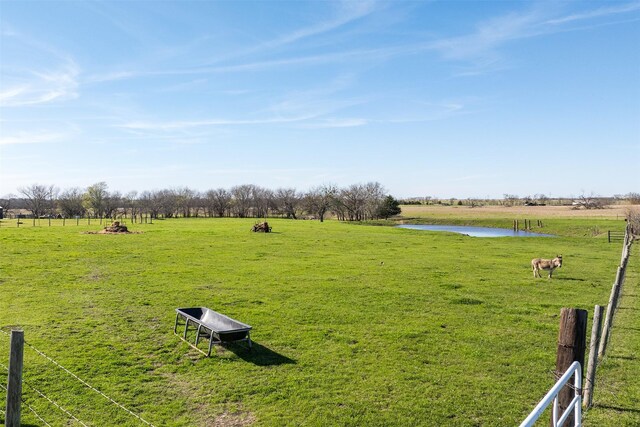 view of community featuring a water view, a lawn, and a rural view
