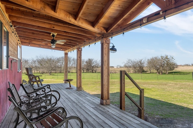 wooden deck with a rural view, a ceiling fan, and a lawn
