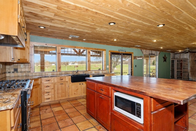 kitchen with butcher block countertops, white microwave, gas range, and wood ceiling