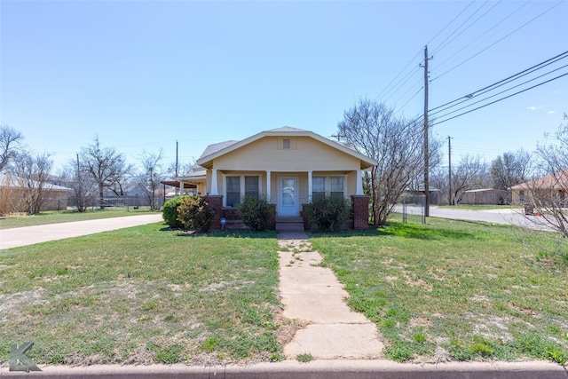 bungalow featuring a front lawn, brick siding, and driveway