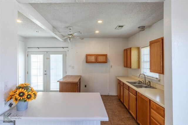 kitchen featuring a wealth of natural light, visible vents, brown cabinets, and a sink