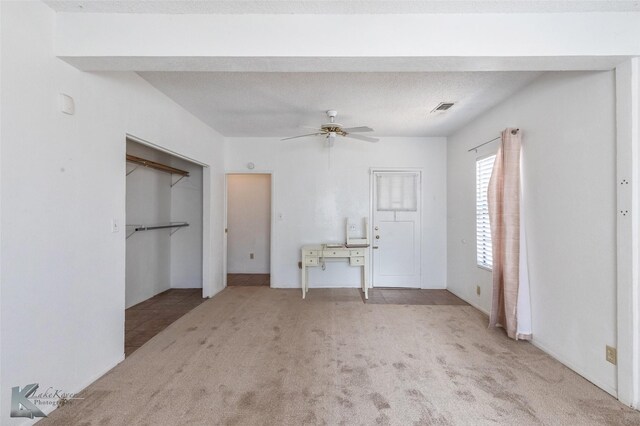 unfurnished bedroom with visible vents, light colored carpet, ceiling fan, and a textured ceiling