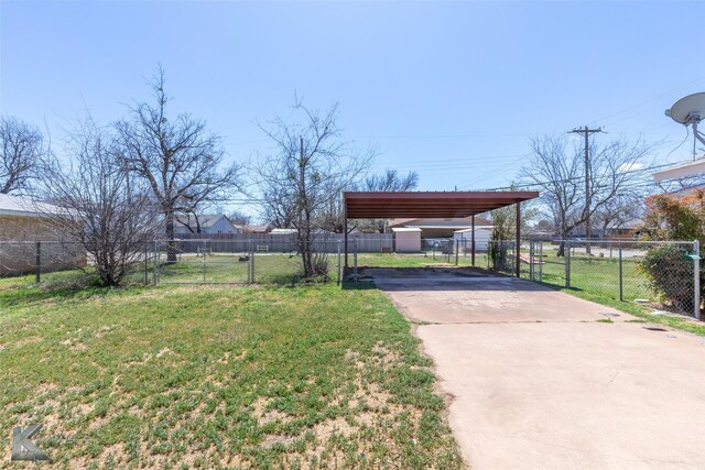 view of yard with a gate, a detached carport, concrete driveway, and fence