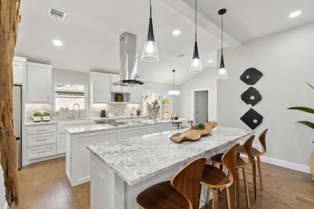 1105 Northpark Dr, Richardson, TX 75081 - kitchen featuring a kitchen island, island exhaust hood, a sink, tasteful backsplash, and white cabinets
