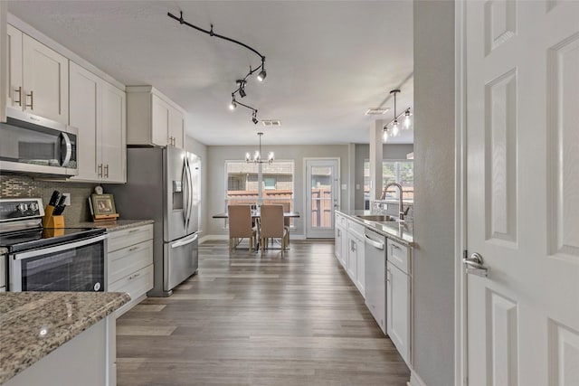 kitchen featuring light wood-style flooring, a sink, decorative backsplash, white cabinets, and appliances with stainless steel finishes