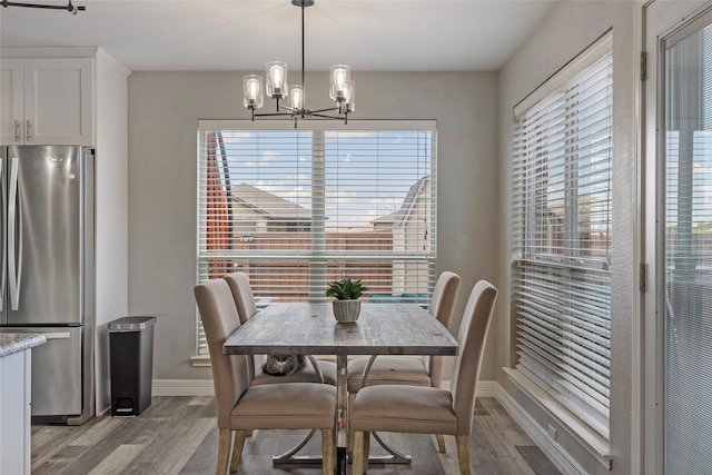 dining room with light wood-type flooring, baseboards, and a notable chandelier