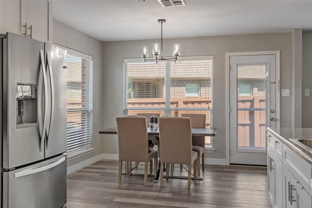 dining space featuring visible vents, baseboards, an inviting chandelier, and wood finished floors