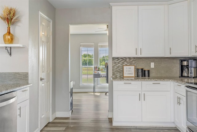 kitchen featuring stainless steel dishwasher, white cabinets, wood finished floors, and tasteful backsplash