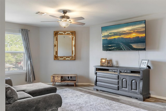 living area featuring baseboards, wood finished floors, visible vents, and ceiling fan