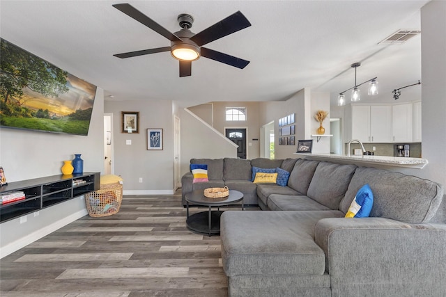 living area featuring visible vents, baseboards, ceiling fan, stairway, and wood finished floors