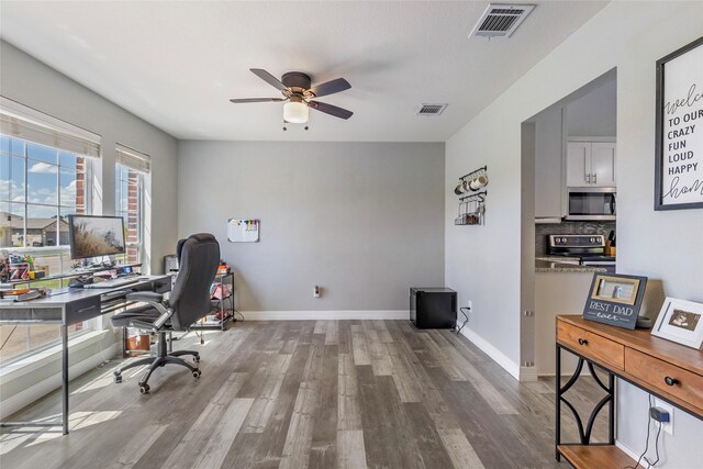 office space with wood finished floors, a ceiling fan, visible vents, and baseboards
