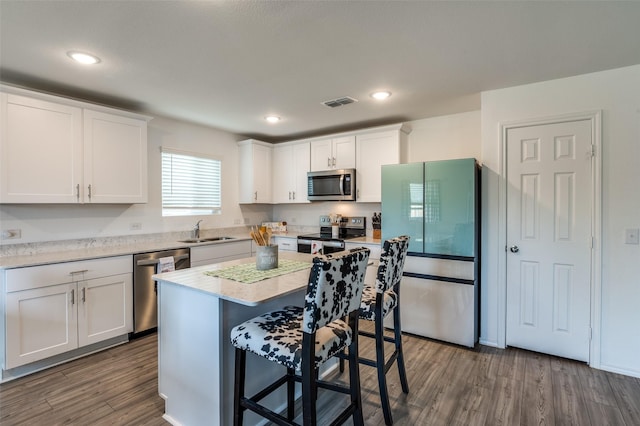 528 Lake Erie Dr, Princeton, TX 75407 - kitchen featuring white cabinets, a breakfast bar, stainless steel appliances, a sink, and dark wood-style floors