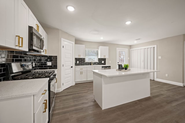 1010 Belew St, Irving, TX 75061 - kitchen featuring backsplash, dark wood finished floors, a center island, white cabinetry, and stainless steel appliances
