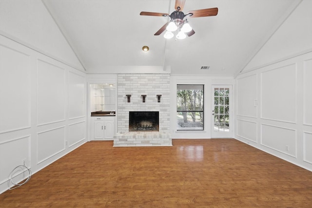 2616 Appledale Ln, Dallas, TX 75287 - unfurnished living room featuring a decorative wall, lofted ceiling, ceiling fan, wood finished floors, and a brick fireplace