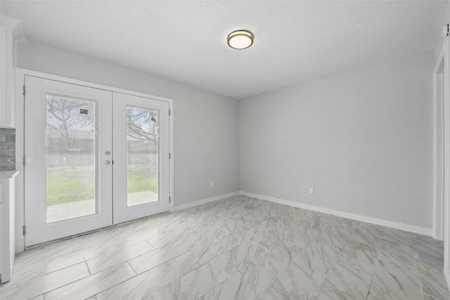 empty room featuring marble finish floor, baseboards, and french doors