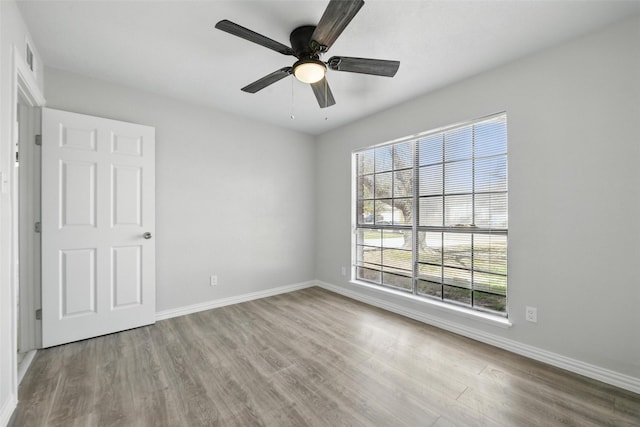 unfurnished room with wood finished floors, a wealth of natural light, and baseboards