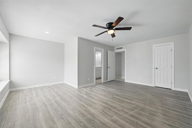 interior space with ensuite bath, baseboards, wood finished floors, and visible vents